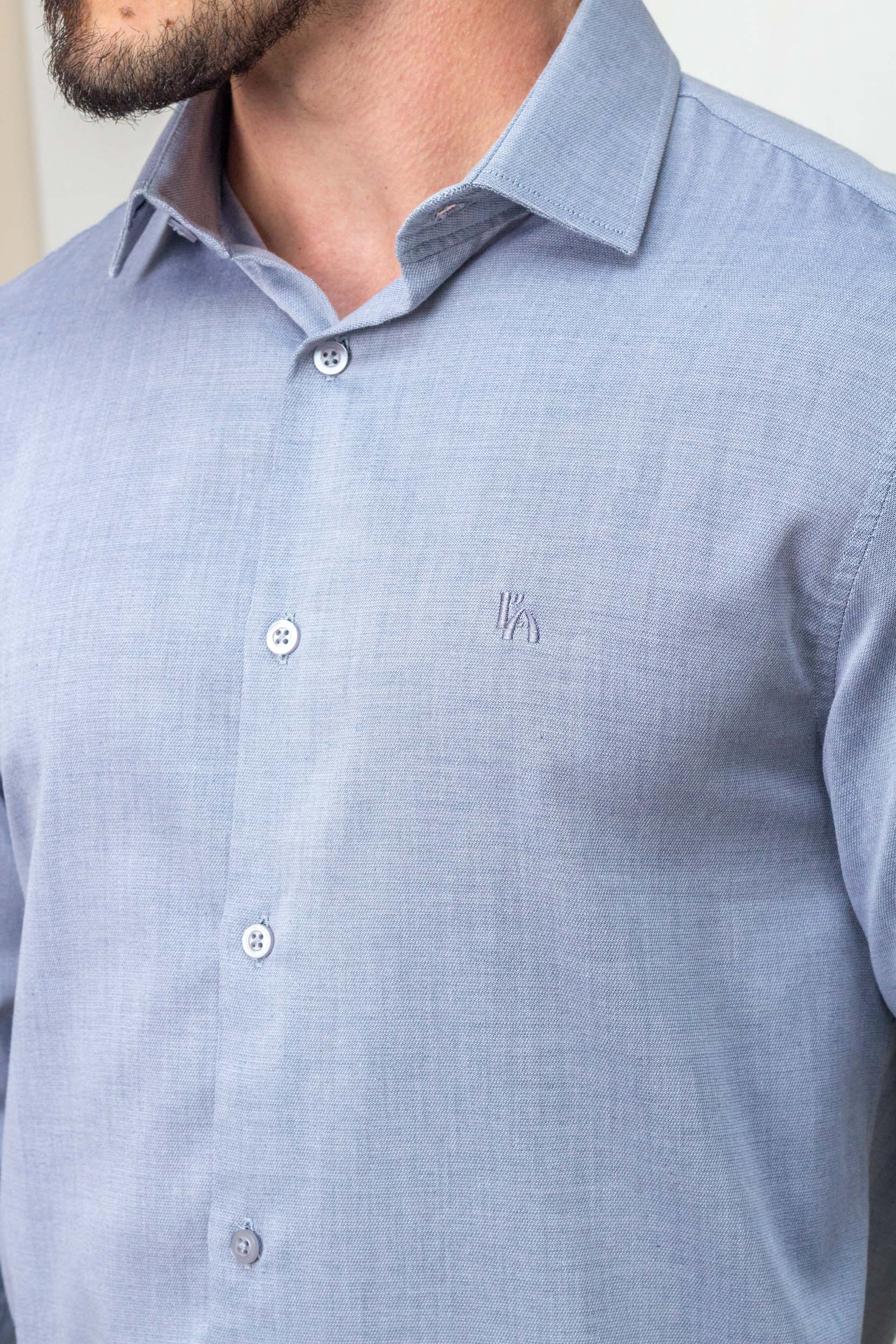 Detalhe macro do tecido texturizado e logo bordado da camisa L'Auttore